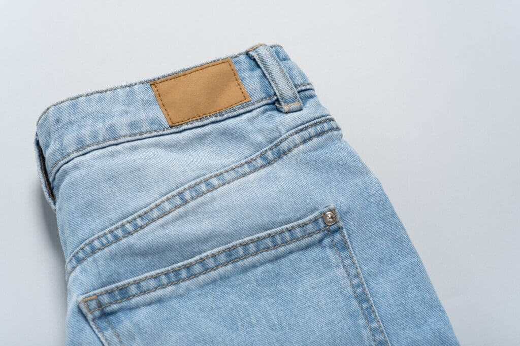 Mockup empty detailed close-up of blank grungy leather label on blue denim suitable gray background