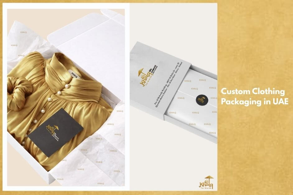 Custom Clothing Packaging in UAE showing a premium white rigid apparel box opened to reveal a neatly folded gold dress wrapped in branded tissue paper, accompanied by a black clothing tag and a matching branded drawer-style box with custom stickers, demonstrating high-end fashion packaging for brands in Dubai, Sharjah, Ajman, and Abu Dhabi.
