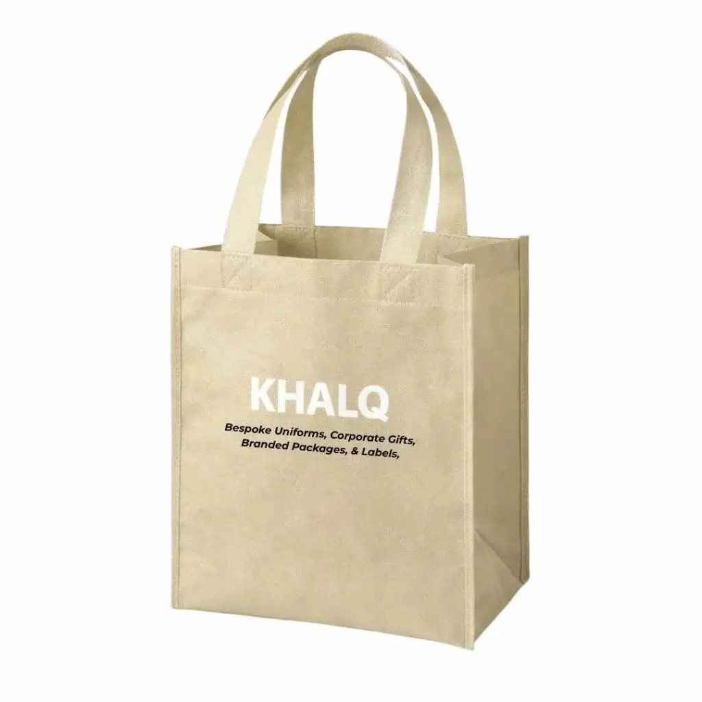 Ivory-colored box bottom non-woven tote bag with loop handles, standing upright with a square base, printed with the KHALQ logo and branding text on the front, designed for custom promotional use in Dubai, UAE.
