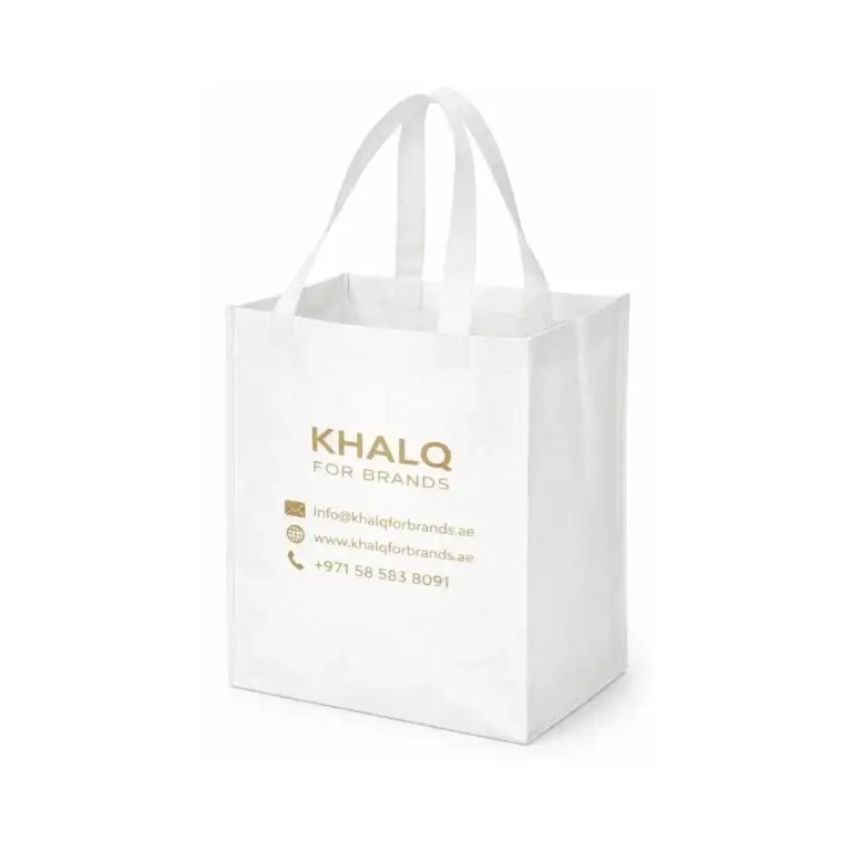 White premium non woven shopping bag with sturdy handles, made from high-quality non woven fabric, featuring gold printed “KHALQ FOR BRANDS” text and contact details, displayed as a reusable, eco-friendly shopping bag for businesses in Dubai, UAE.